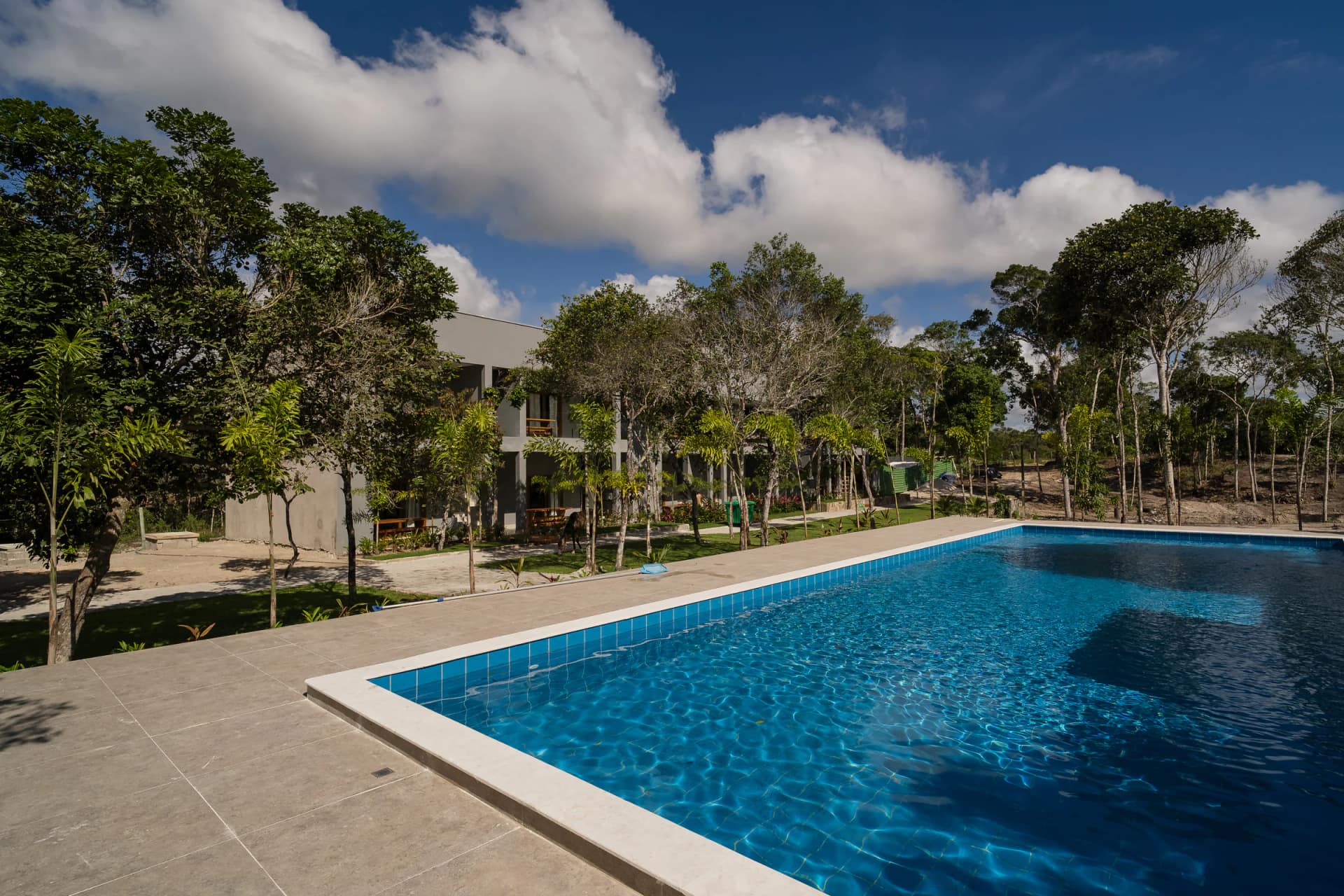 Vista ampla da piscina em dia de sol no Residencial Marinho, Arraial d’Ajuda.