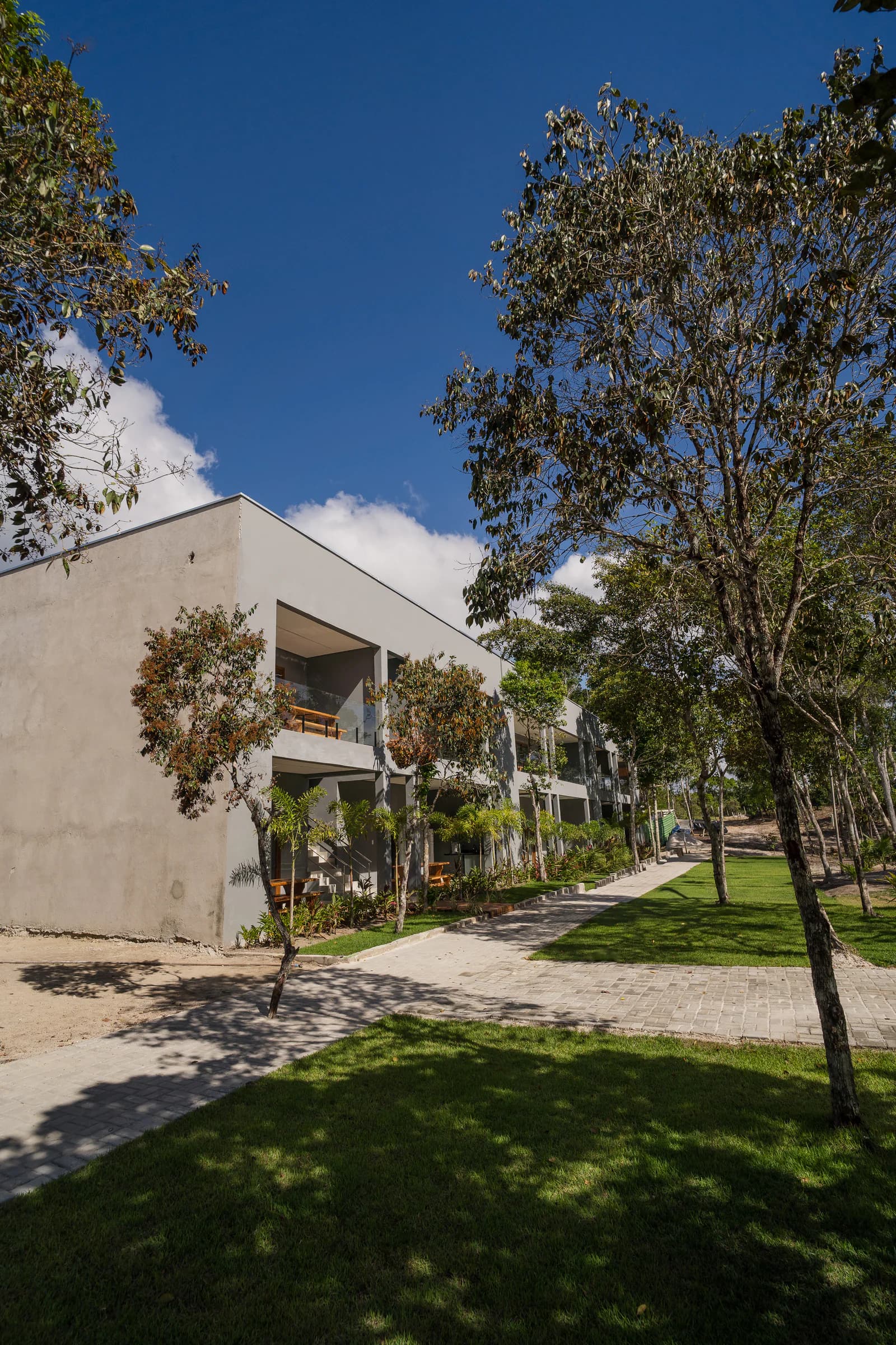 Fachada lateral entre árvores e jardins no Residencial Marinho, Arraial d’Ajuda.
