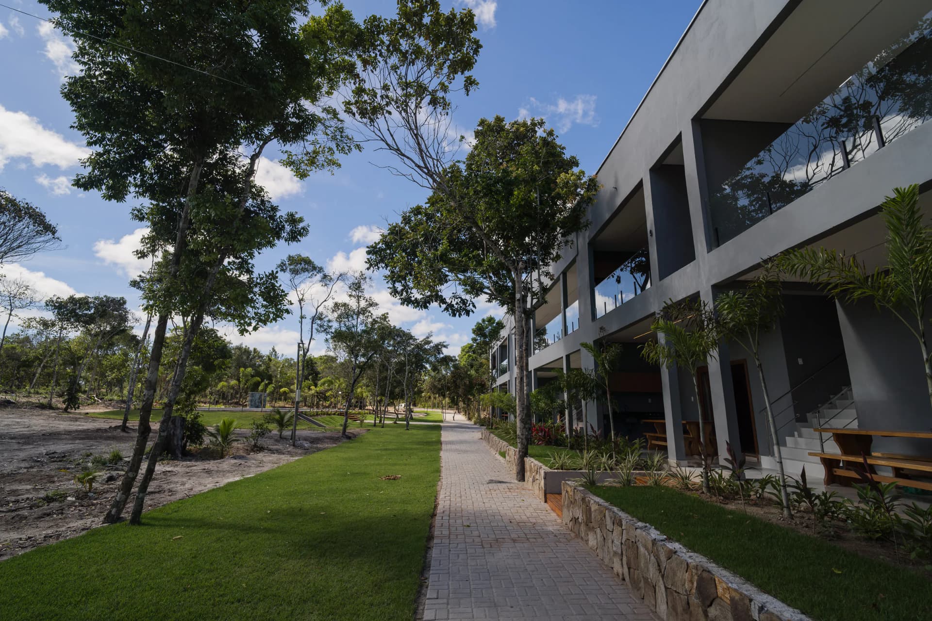 Passeio arborizado diante das suítes no Residencial Marinho, Arraial d’Ajuda.
