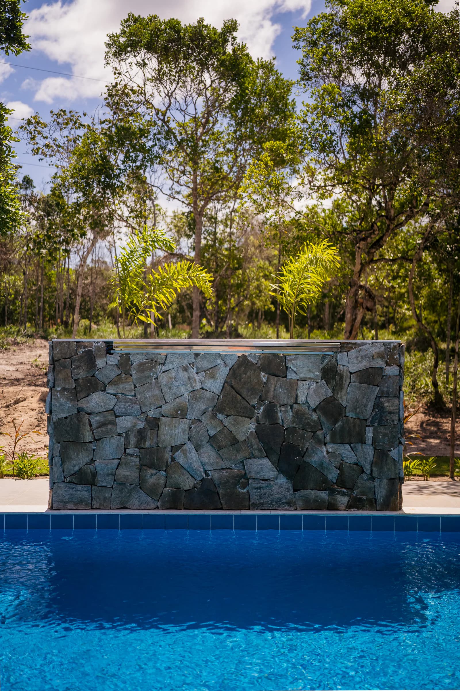 Piscina e parede de pedra em vista vertical no Residencial Marinho, Arraial d’Ajuda.