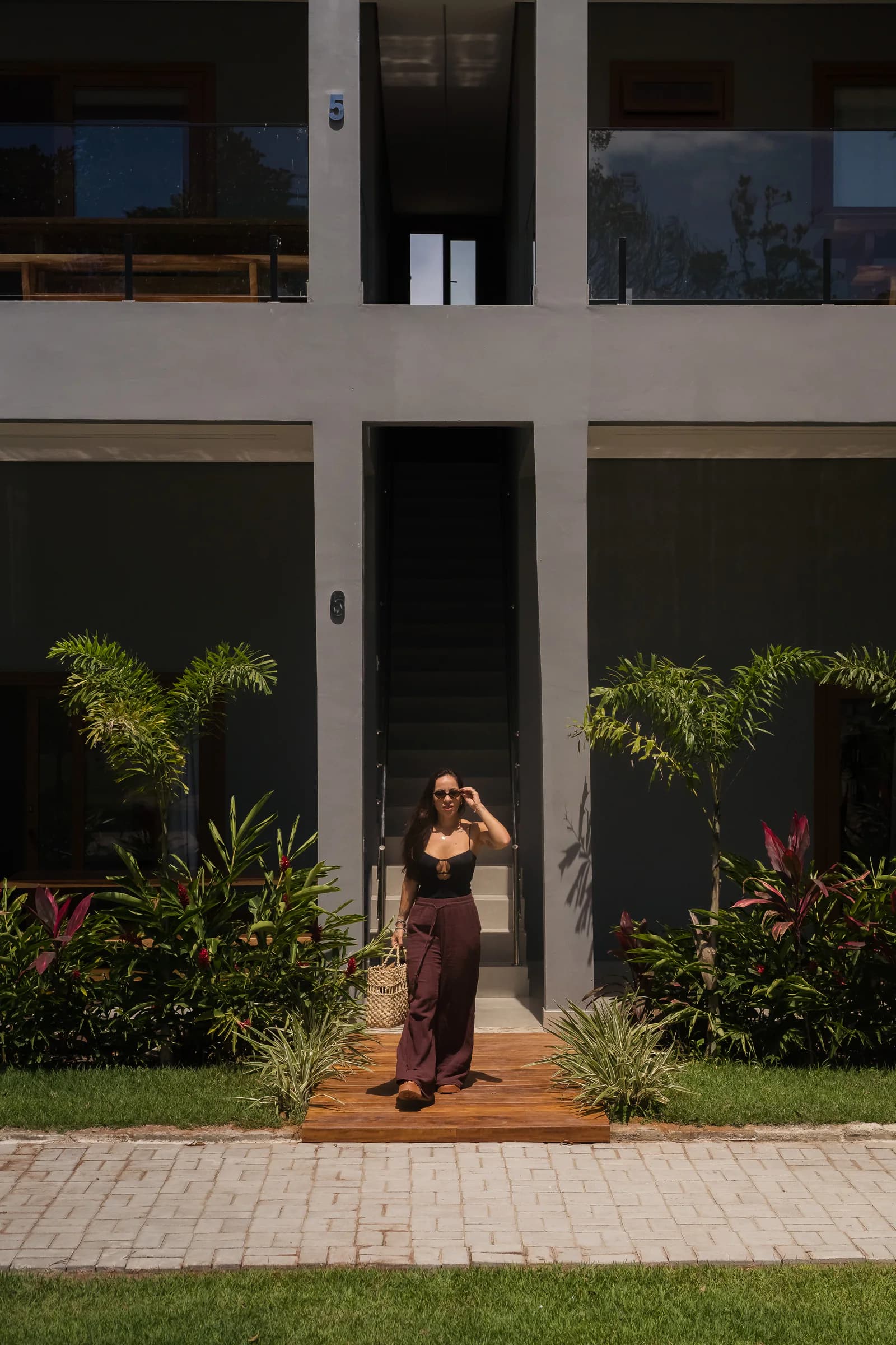 Pessoa chegando pela entrada ajardinada no Residencial Marinho, Arraial d’Ajuda.