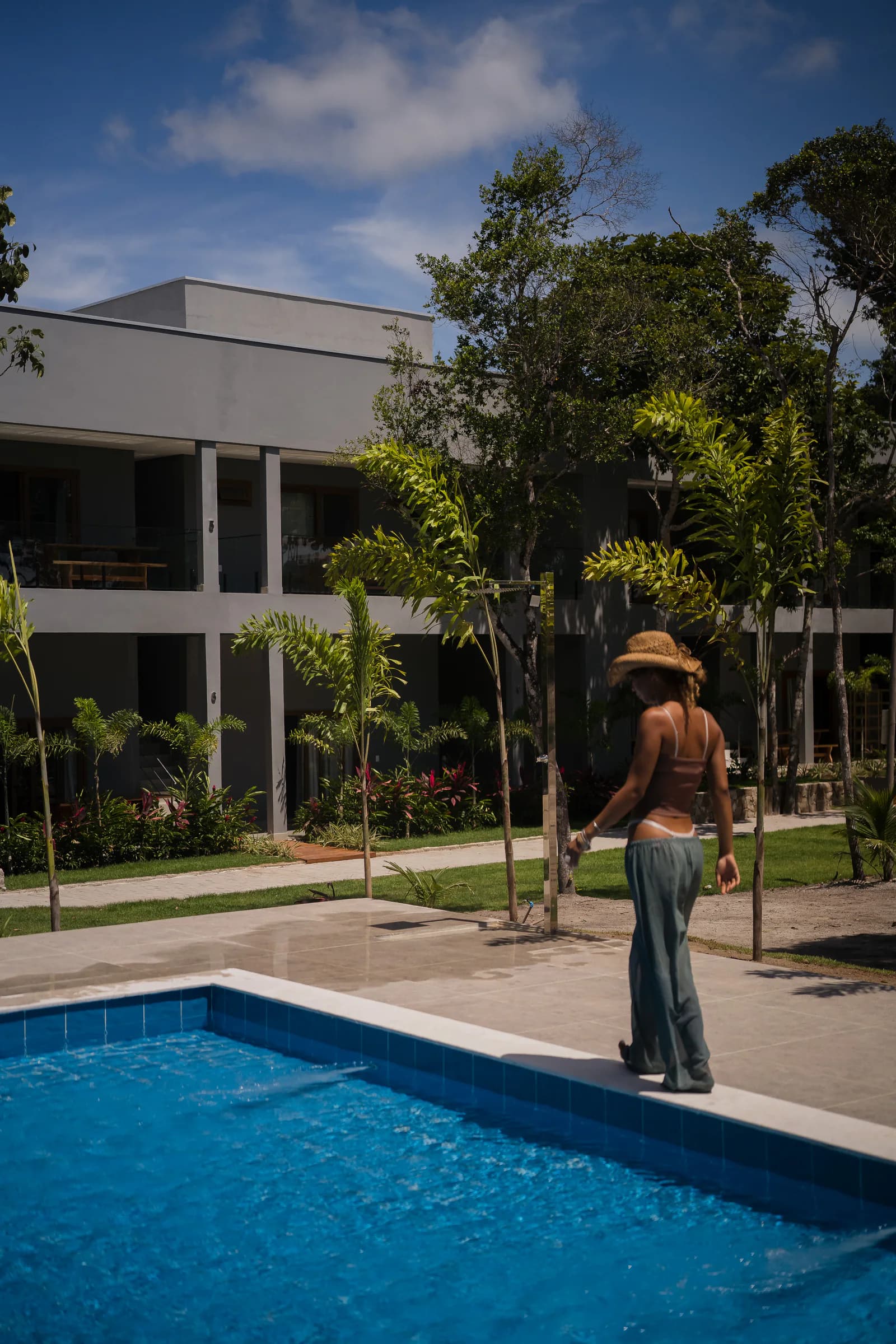 Pessoa caminhando junto à piscina no Residencial Marinho, Arraial d’Ajuda.